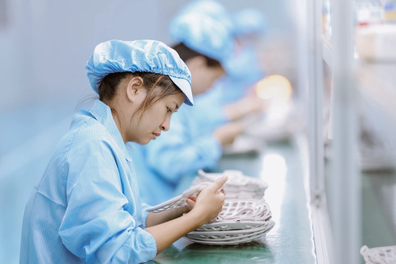 Worker assembling LED face mask components on production line